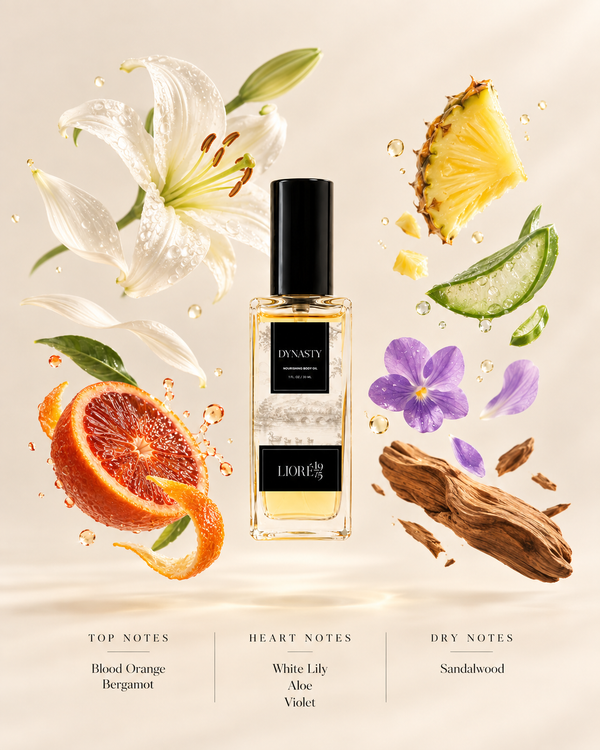 A perfume style body oil bottle labeled 'DYNASTY' centered on a warm cream background, surrounded by floating botanical and fruit elements including white lily flowers, a sliced blood orange, pineapple, aloe vera, purple violets, bark pieces, and water droplets. Text at the bottom lists top, heart, and dry notes.